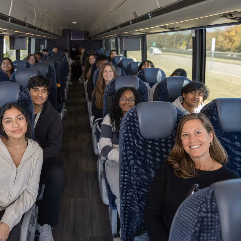 Group boarding a white charter bus for School Transportation transportation in Wellington